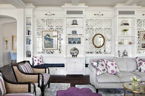 svetainė, pilka sofa, violetinės ir baltos dekoratyvinės pagalvėlės, baltos spintelės, violetinė pufas