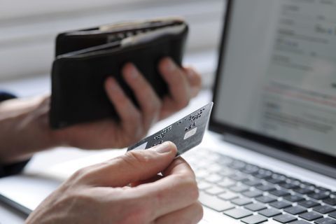 Rankoje laikoma kreditinė kortelė ir piniginė nešiojamu kompiuteriu
