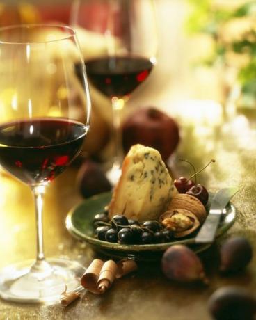 Raudonasis vynas su užkandžių patiekalais iš mėlynojo sūrio, vynuogių, graikinių riešutų ir figų